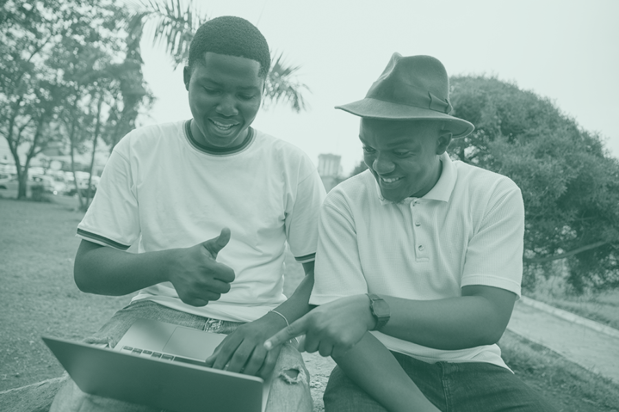 Two people sharing a laptop outdoors